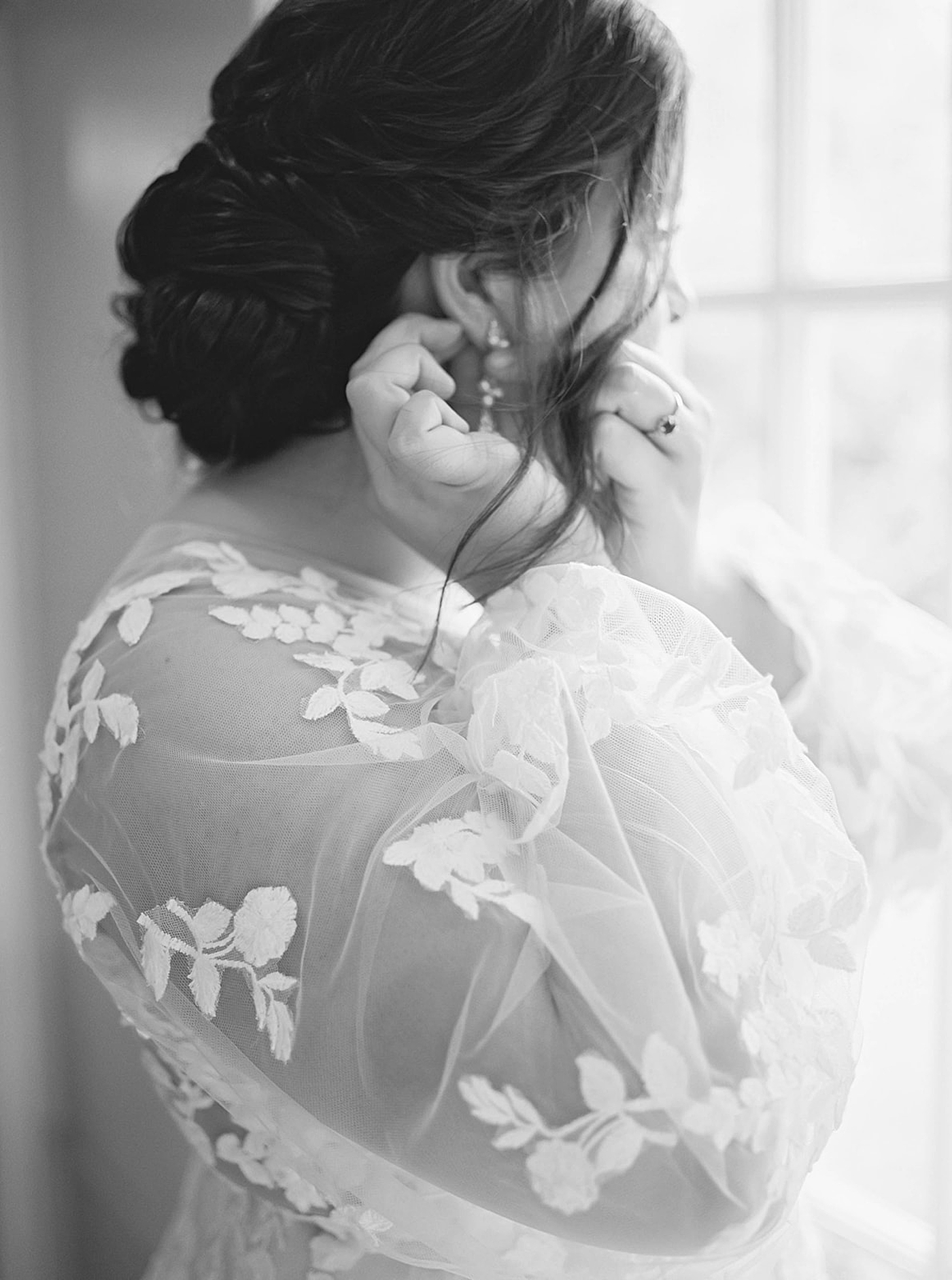 Black and white image of bride putting on her earrings | Carters Event Co