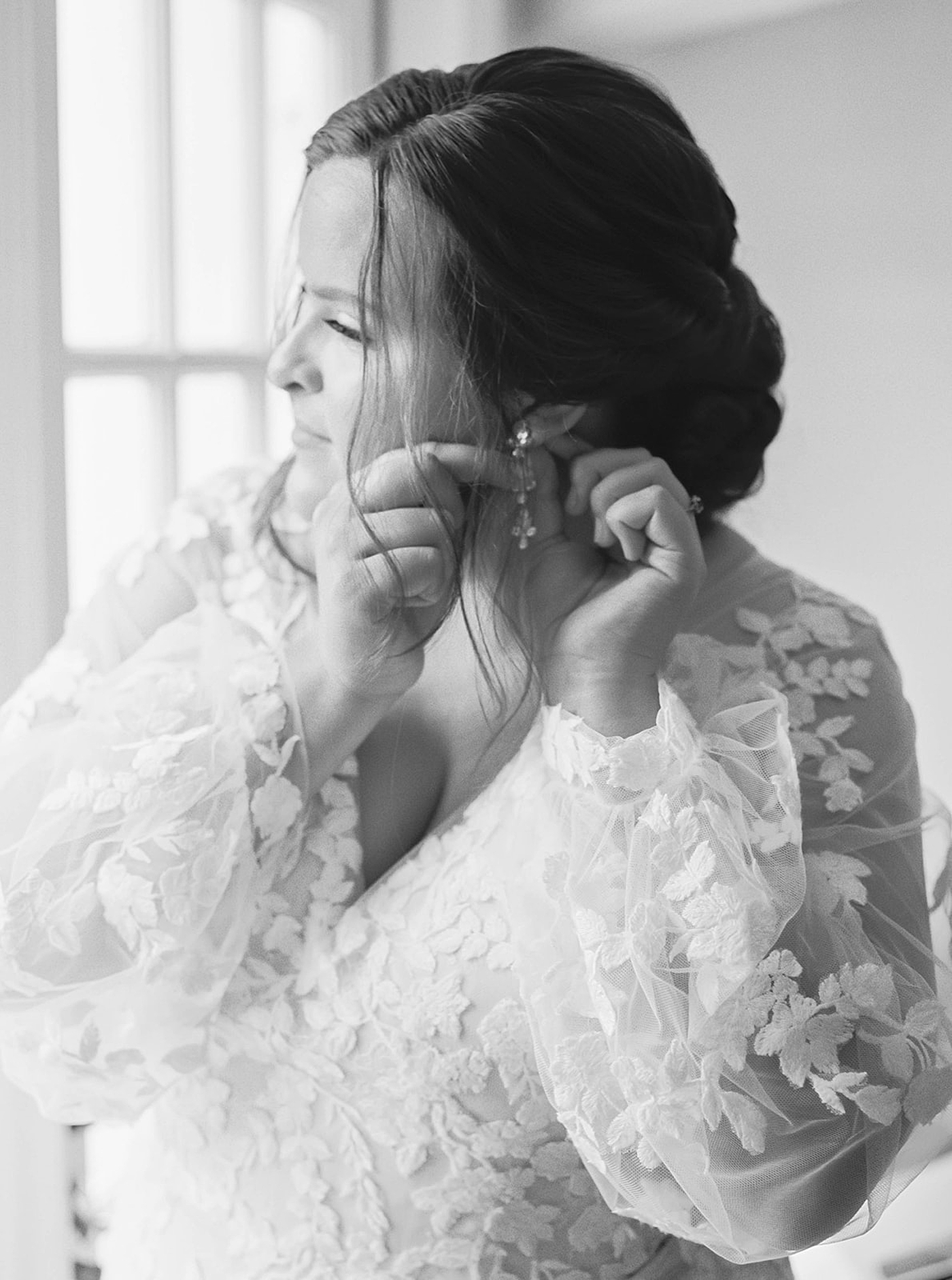 Black and white image of bride putting in her earrings | Carters Event Co