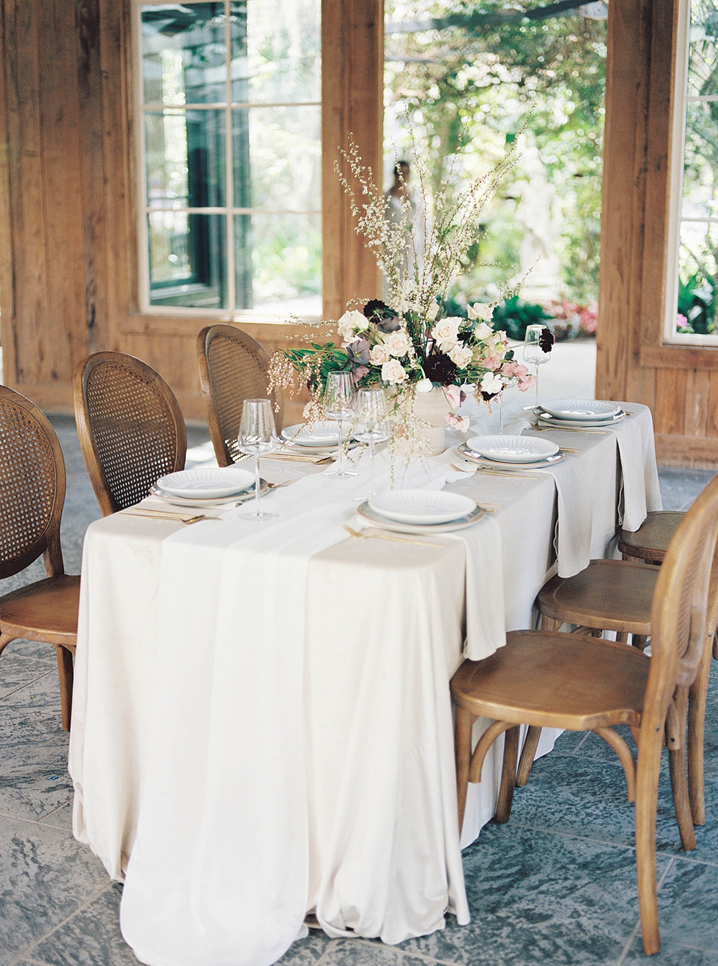 Wedding table with light cream linens and flowers with wooden chairs | Carters Event Co