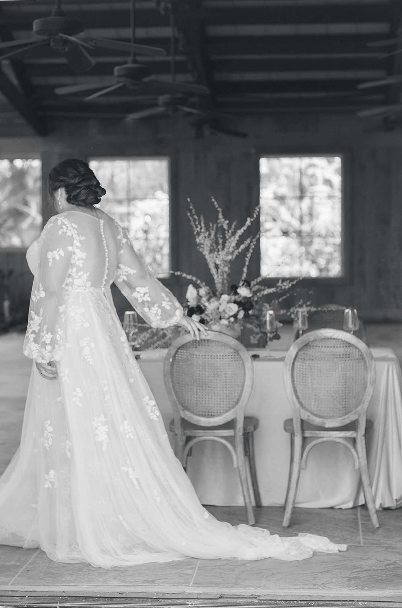 Black and white image of bride walking by a table | Carters Event Co