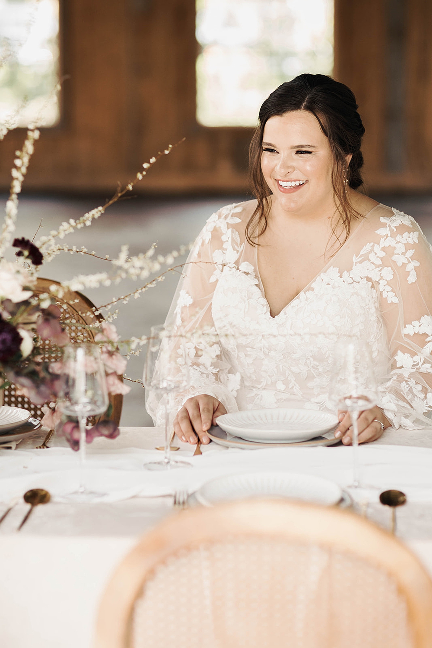 Bride in a lace gown smiling sitting at a table | Carters Event Co