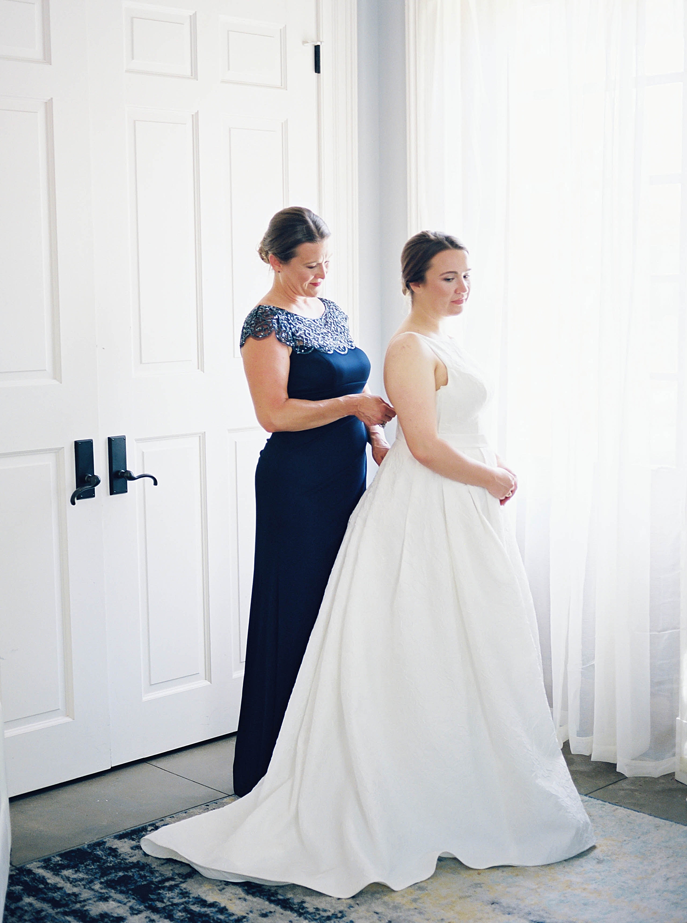 Bride bring helped into her gown | Carters Event Co