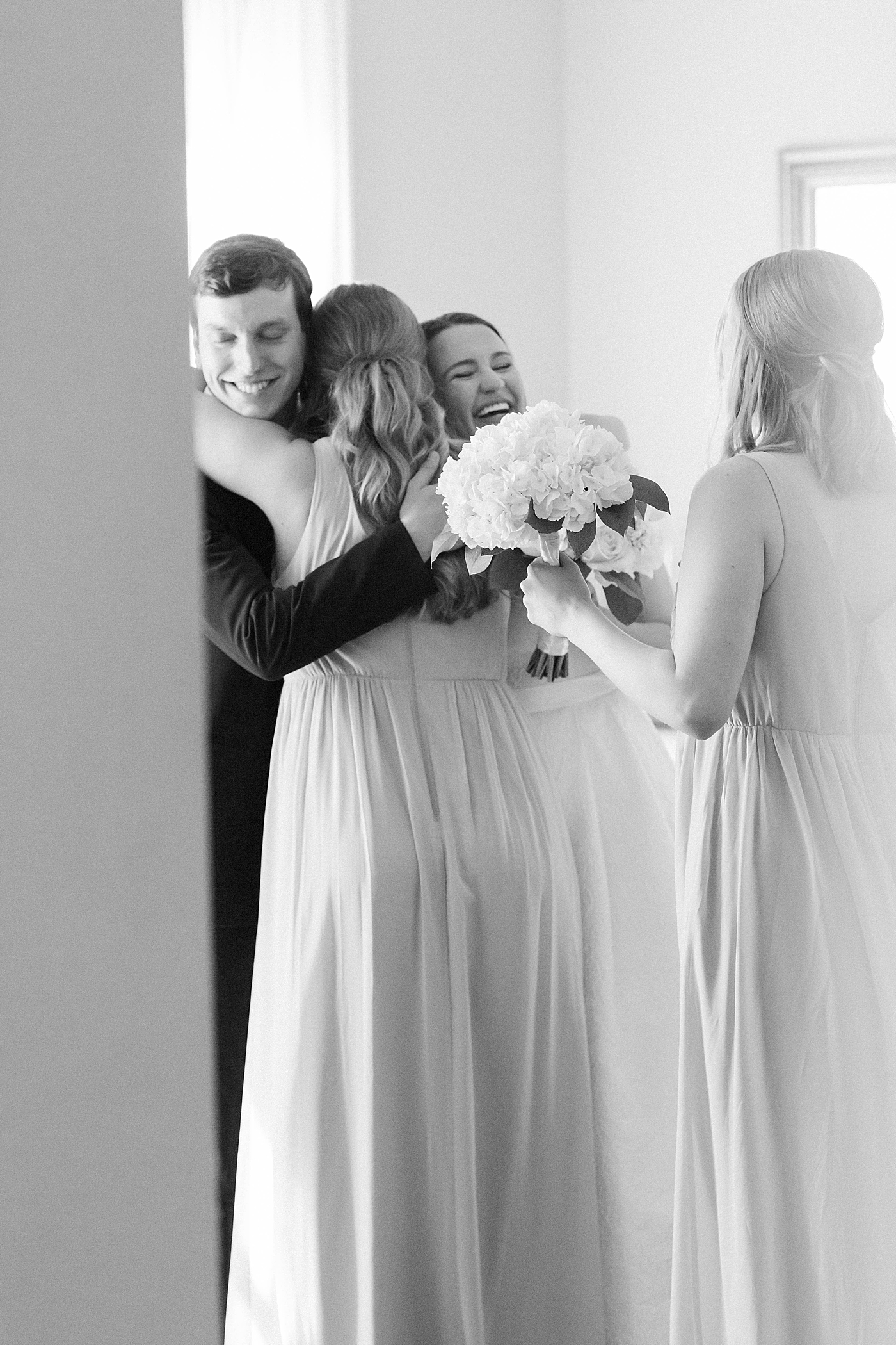 Black and white image of bridesmaid embracing bride and groom during their Intimate spring wedding | Carters Event Co
