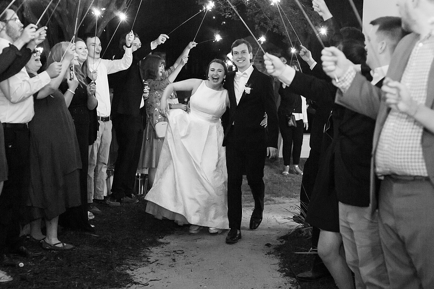 Black and white image of bride and groom running through sparklers during their Intimate spring wedding | Carters Event Co