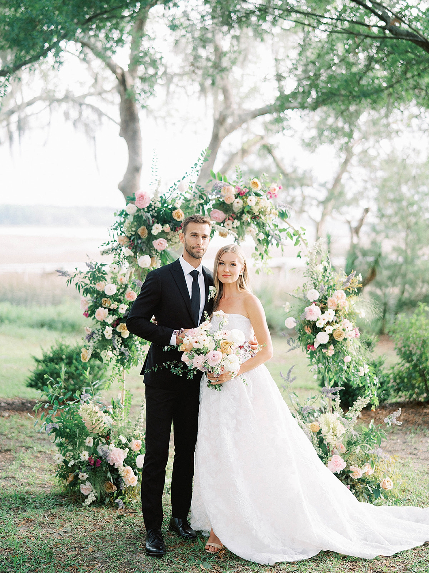 Bride and groom pose in front of their wedding arbor | Carters Event Co