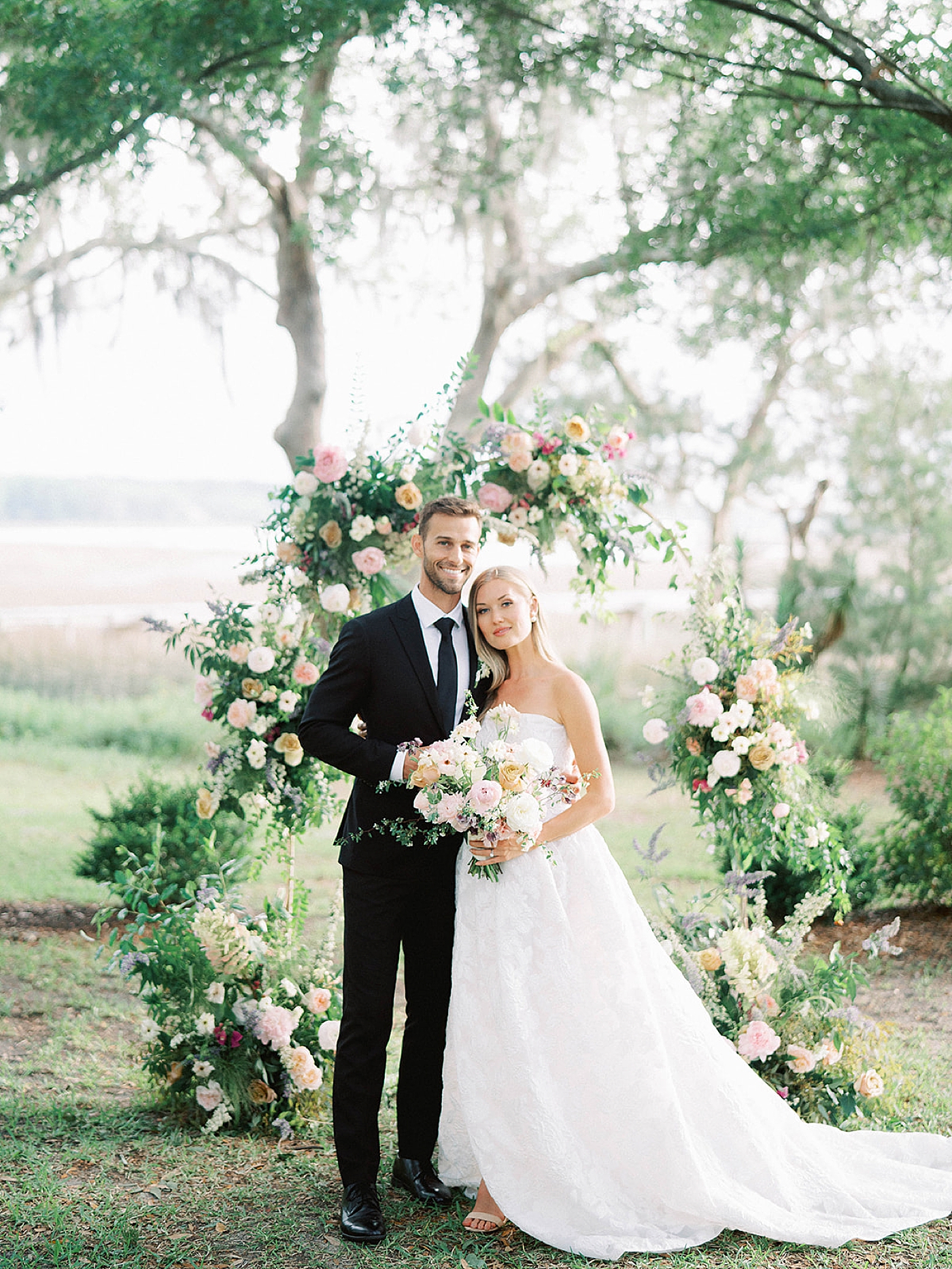 Bride and groom smiling in front of their arbor | Carters Event Co