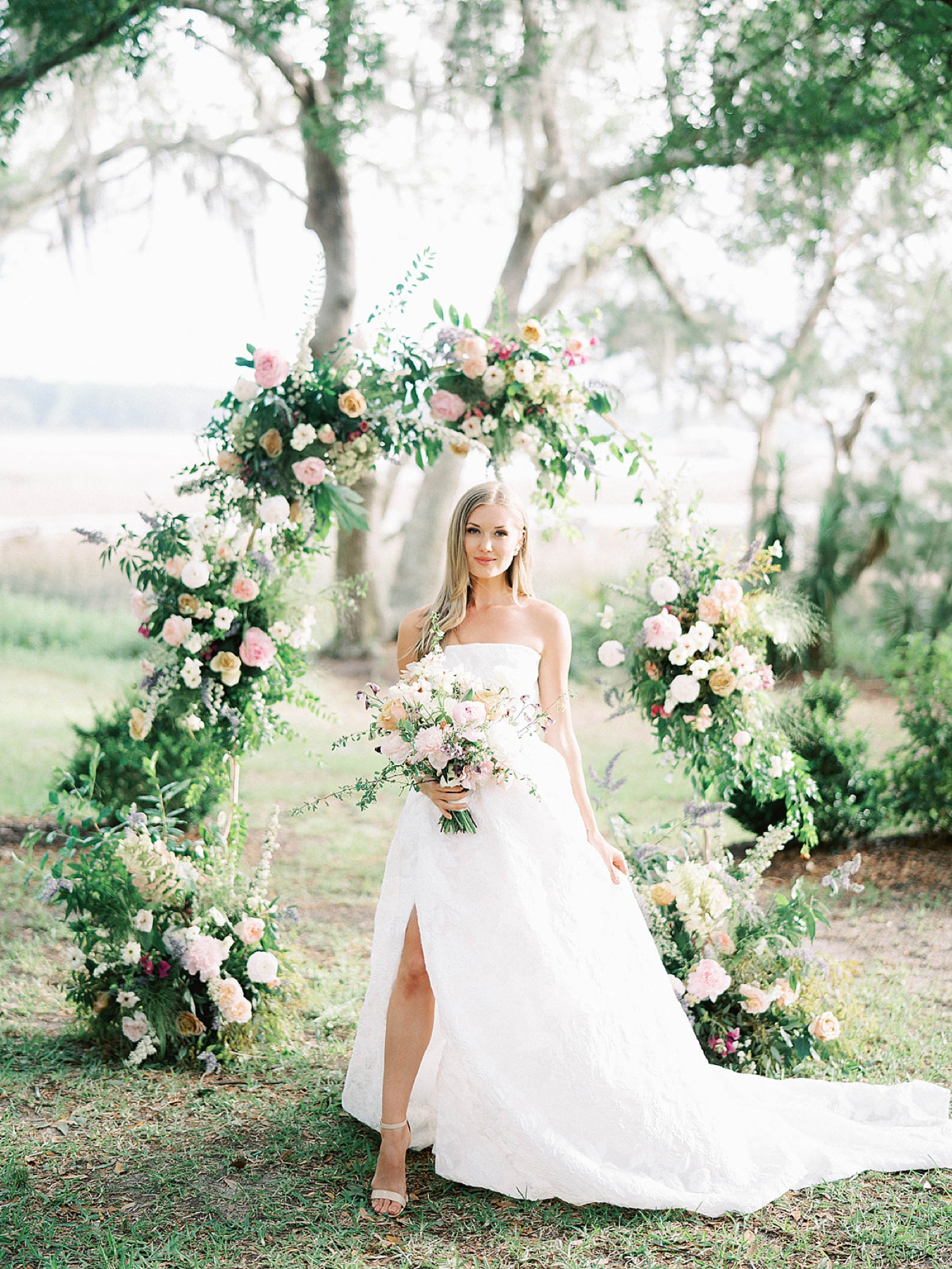 Bride smiling in front of floral arbor | Carters Event Co